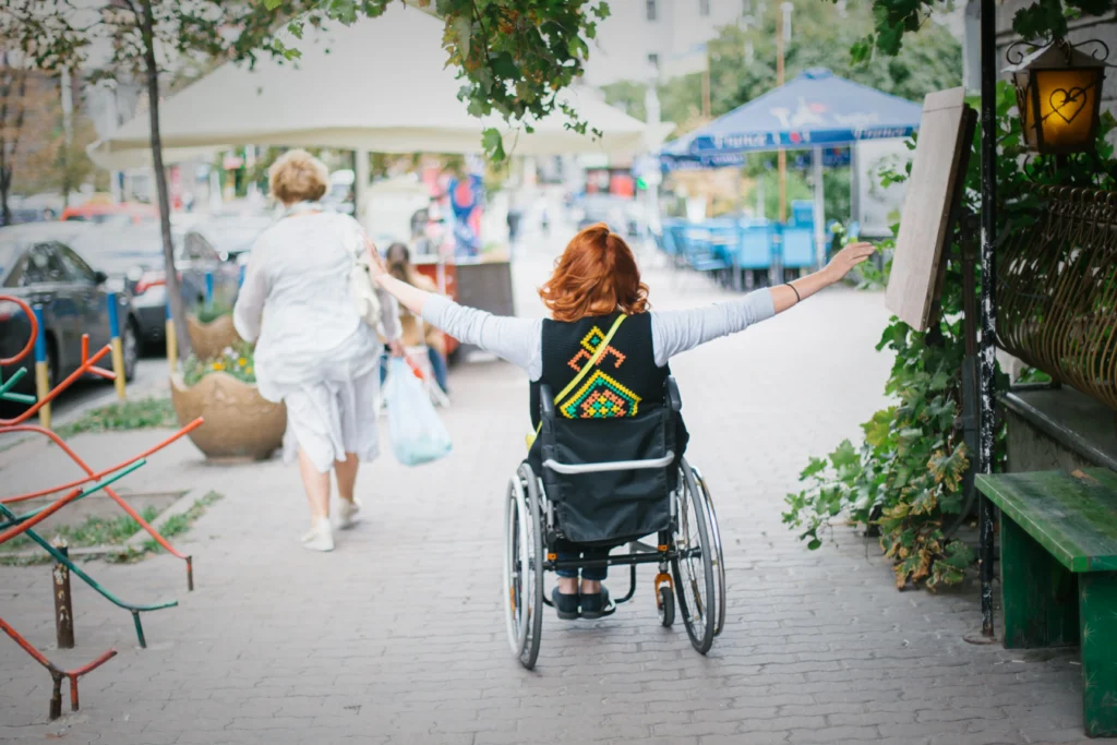 Vista general de una calle con una mujer mostrando felicidad sobre su silla de ruedas