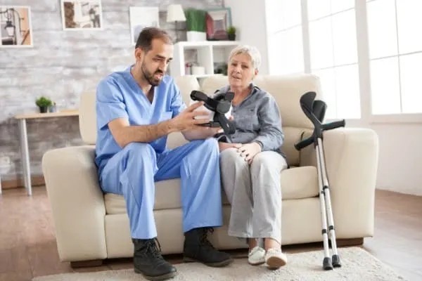 Visita general de una explicación de un enfermero de uno de los aparatos para adultos mayores para caminar después de su lesión.