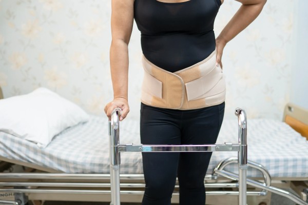 Enfoque de la mitad del cuerpo de una persona recién operada que necesita una andadera como que es un aparato ortopédico.